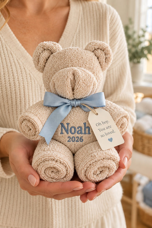 AI-generated concept of the approved towel bear with blue bow and Noah 2026 embroidery